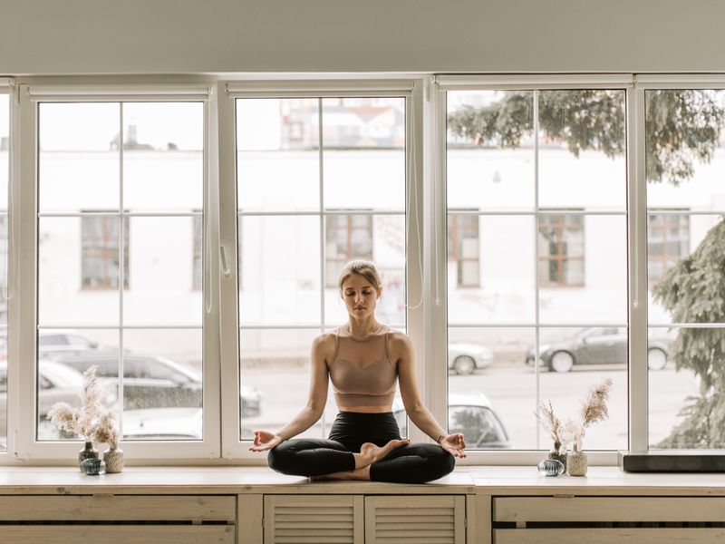 Mujer meditando junto a la ventana